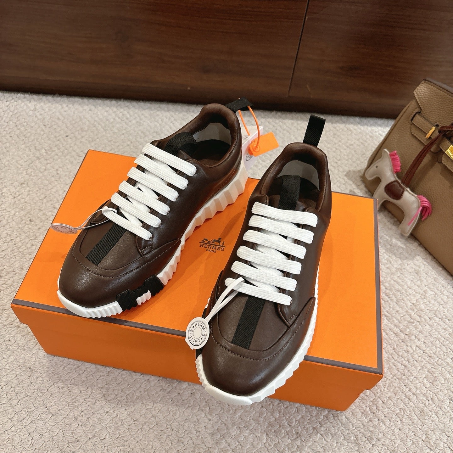 Hermes unisex luxury shoes, dark brown leather, white laces, pair angled on box