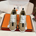 Beige unisex sneakers with white laces, black side stripe, and chunky white tread sole.