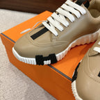 Beige sneaker close-up with white laces, black side panel, and ribbed white midsole.