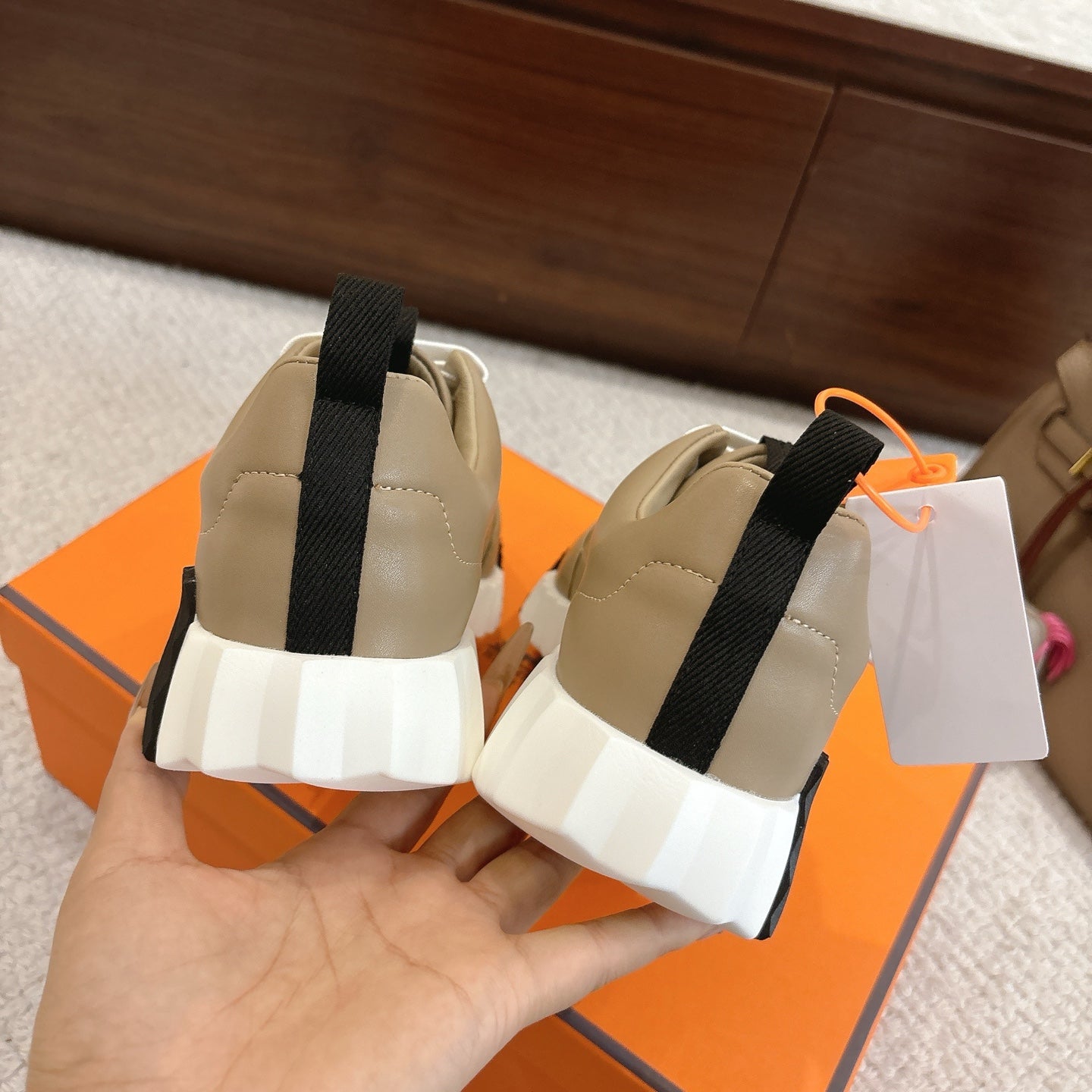 Beige unisex sneakers from back view with black heel tab and chunky white outsole.