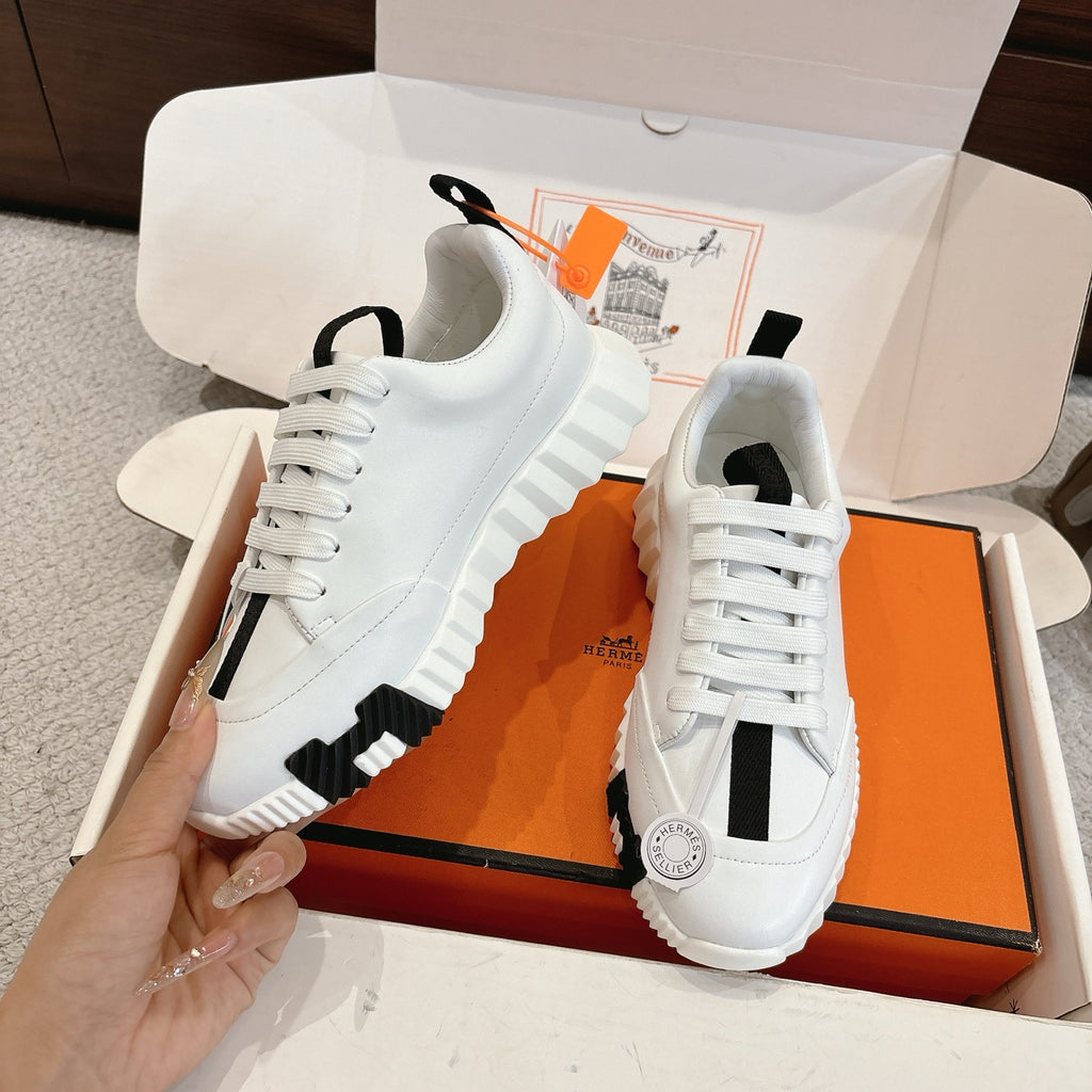 White Hermes sneakers with black accents and lace-up front, angled view of pair.