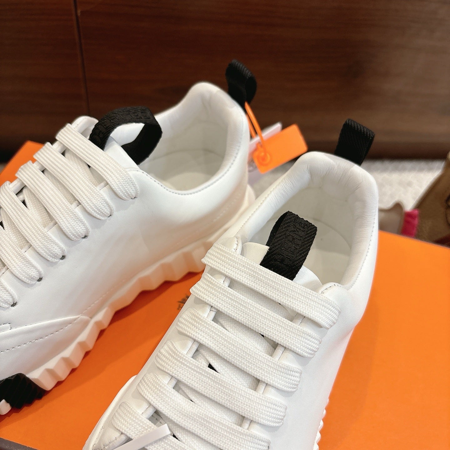 White Hermes sneakers with black heel strap and lace-up, close-up back angle of pair.