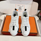 White Hermes sneakers with black strap details and thick sole, front view of pair.
