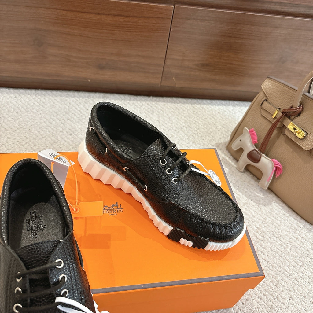 Black leather lace-up shoes with white rugged sole, close side view with tags attached.
