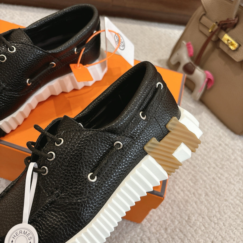 Black leather lace-up shoes with white sole and round eyelets, close angled pair view.