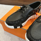 Black leather lace-up shoes with detailed grain texture and white sole, close-up angle.