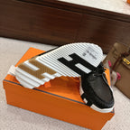 Black leather lace-up shoes showing treaded white outsole, side angle on orange box.