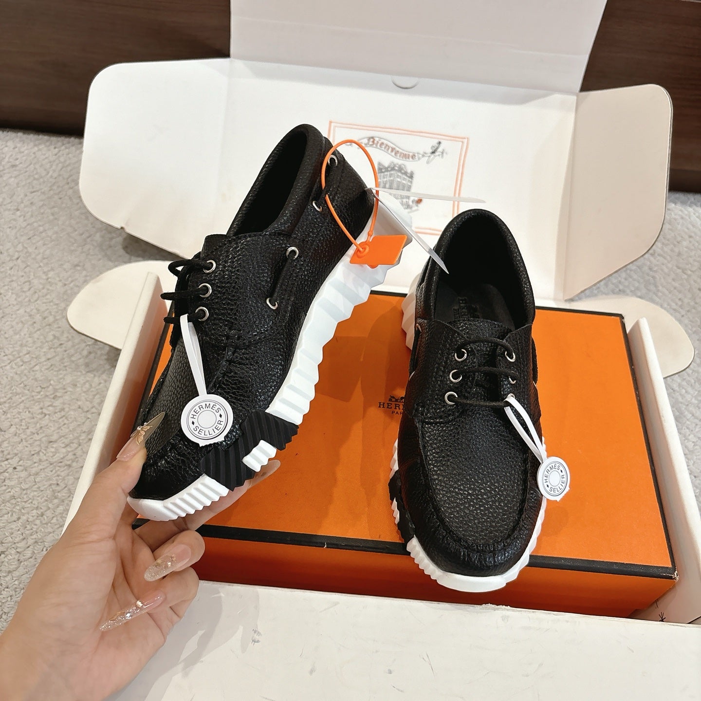 Black leather lace-up shoes with white sole texture, laces and side view on box.