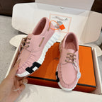 Pink leather unisex sneakers pair, side view with lace-up and ridged rubber sole.