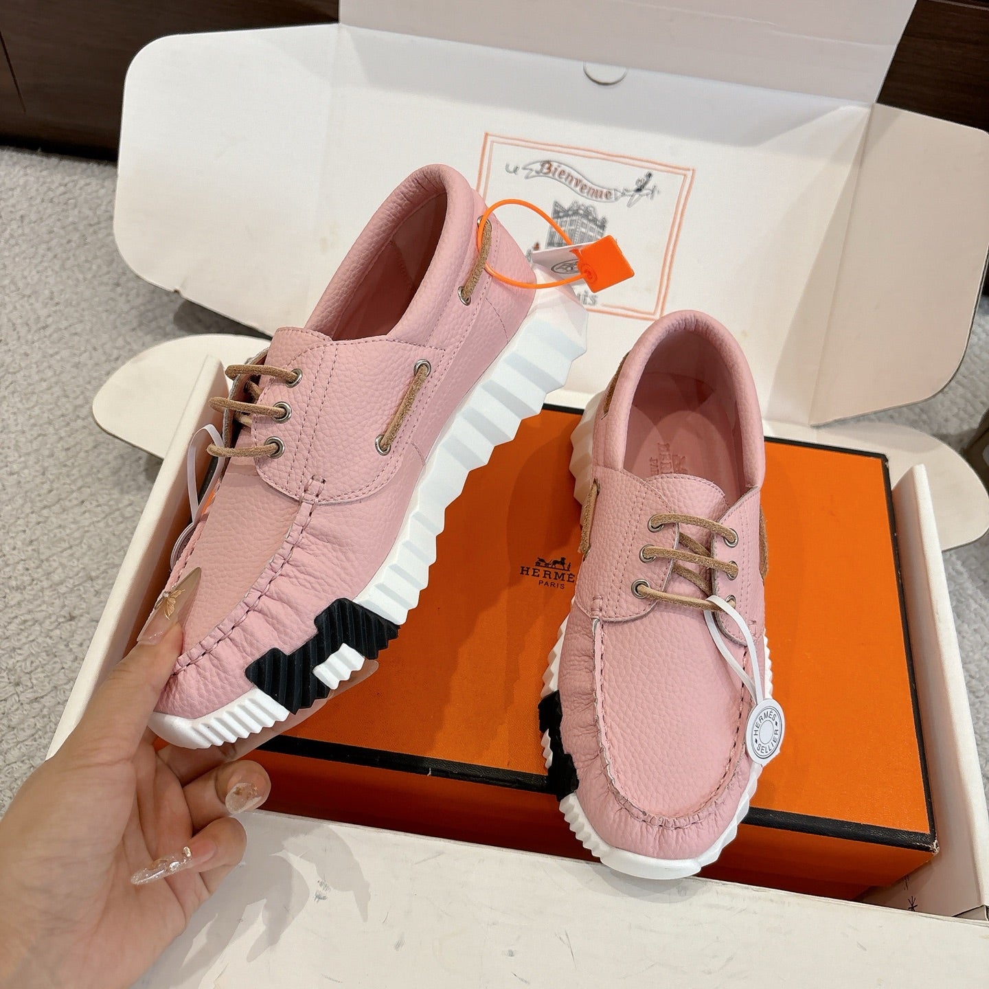 Pink leather unisex sneakers pair, side view with lace-up and ridged rubber sole.