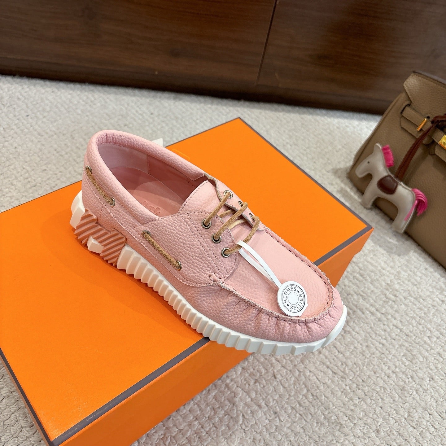 Pink leather unisex sneakers, front-side angle with lace-up and white ridged sole.