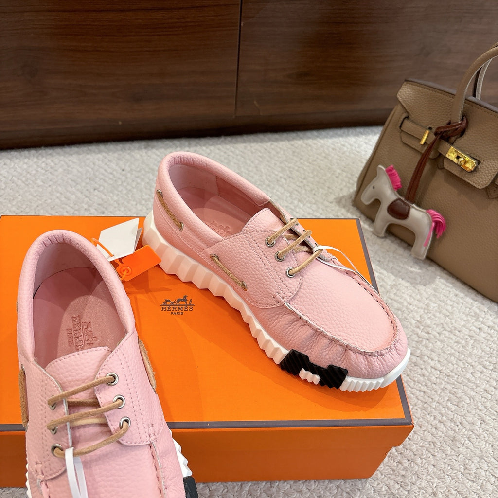 Pink leather unisex sneakers, angled side view showing lace-up and thick cushioned sole.