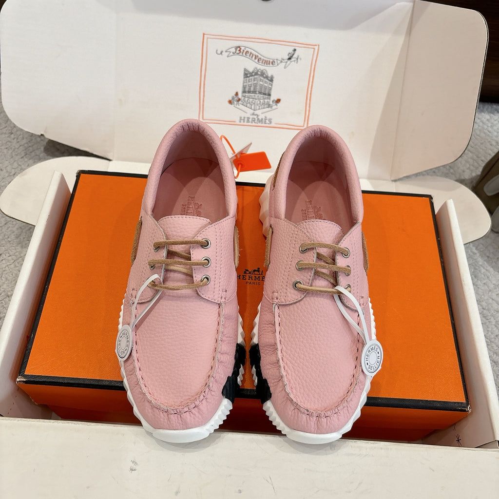 Pink leather unisex sneakers, lace-up with gold eyelets and thick white sole.