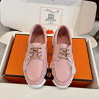 Pink leather unisex sneakers, lace-up with gold eyelets and thick white sole.