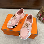 Pink leather unisex sneakers on an orange box, lace-up front with white ridged sole.