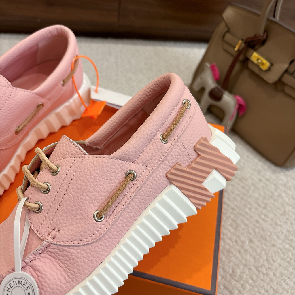 Pink leather unisex sneakers close-up, side profile with lace-up and stacked ridged sole.