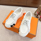 Pair of white leather sneakers with chunky ridged soles and lace-up fronts