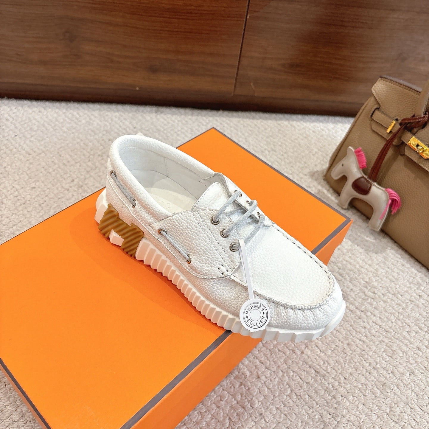 White leather low-top sneakers with gray laces and oval logo patch