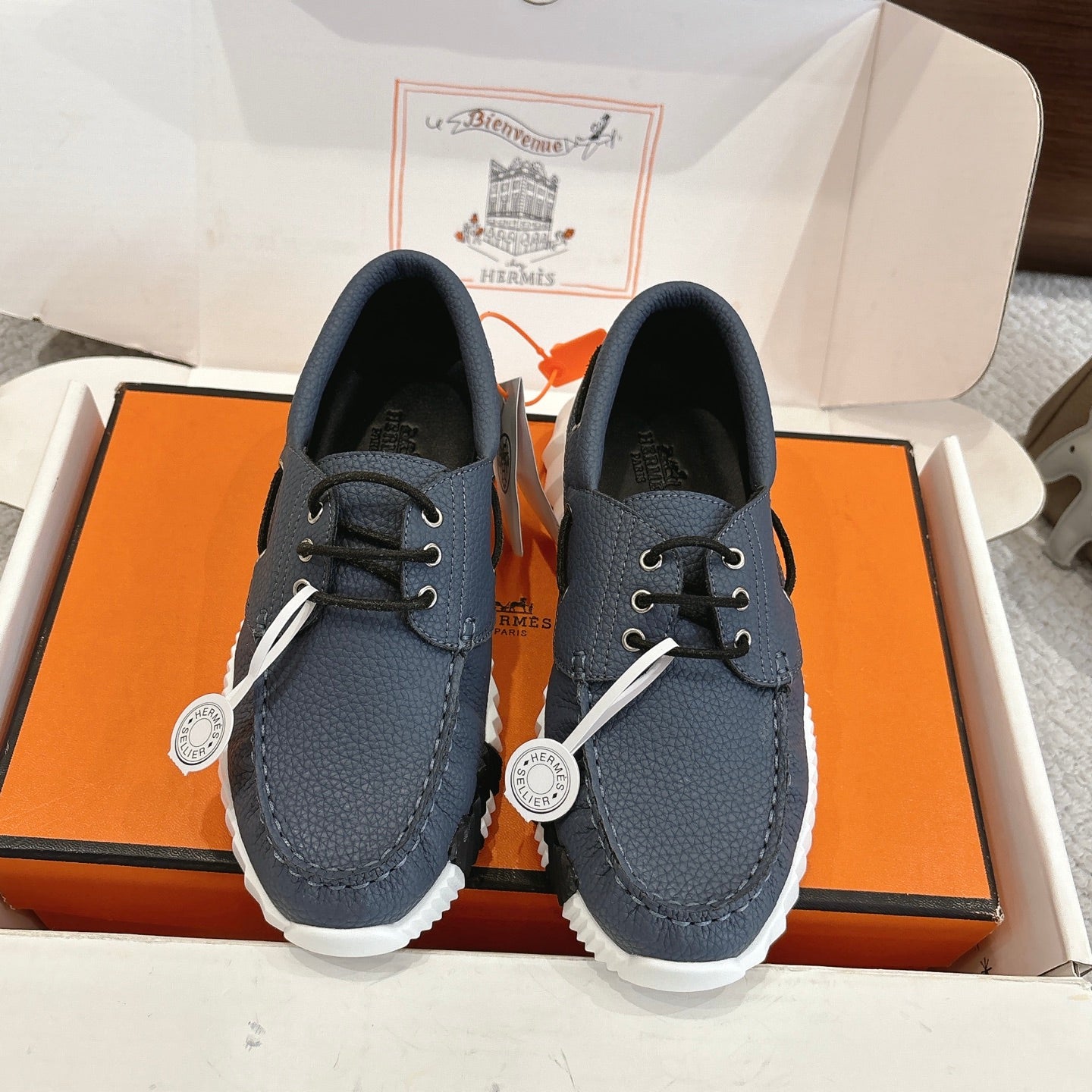 Hermes unisex navy leather lace-up sneakers with chunky white sole and logo charm