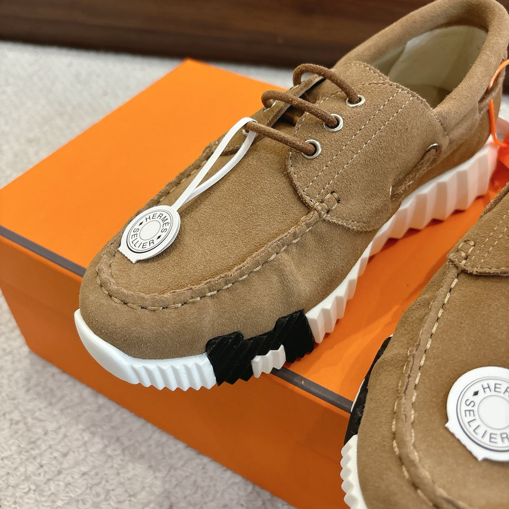 Tan suede lace-up sneaker close-up with white-and-black tread sole and round logo tag