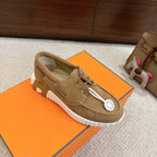 Tan suede lace-up sneakers with white ribbed sole, lace-up eyelets, and logo patch