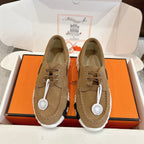 Tan suede lace-up sneakers with white-and-black tread sole and round logo tag