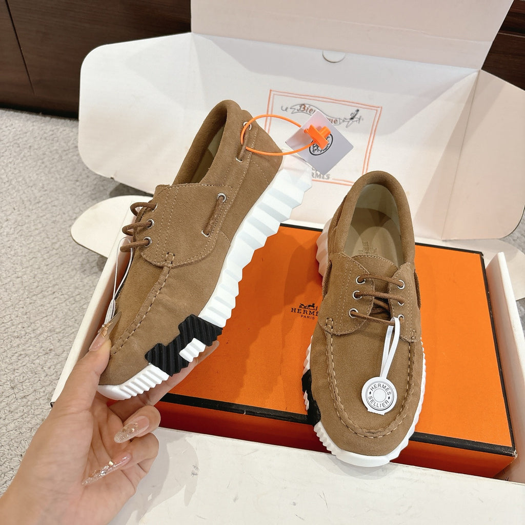 Tan suede lace-up sneakers with ridged white sole, black side detail, and logo tag
