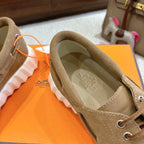 Tan suede sneaker with printed insole, lace-up front, and round logo charm