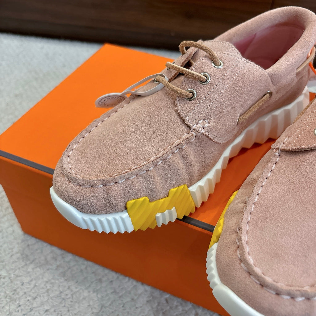 Close-up of beige suede lace-up shoe with white ridged sole and yellow stripe