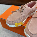 Close-up of beige suede lace-up shoe with white ridged sole and yellow stripe