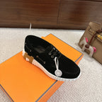 Black lace-up unisex sneaker with white ridged sole and round charm on lace