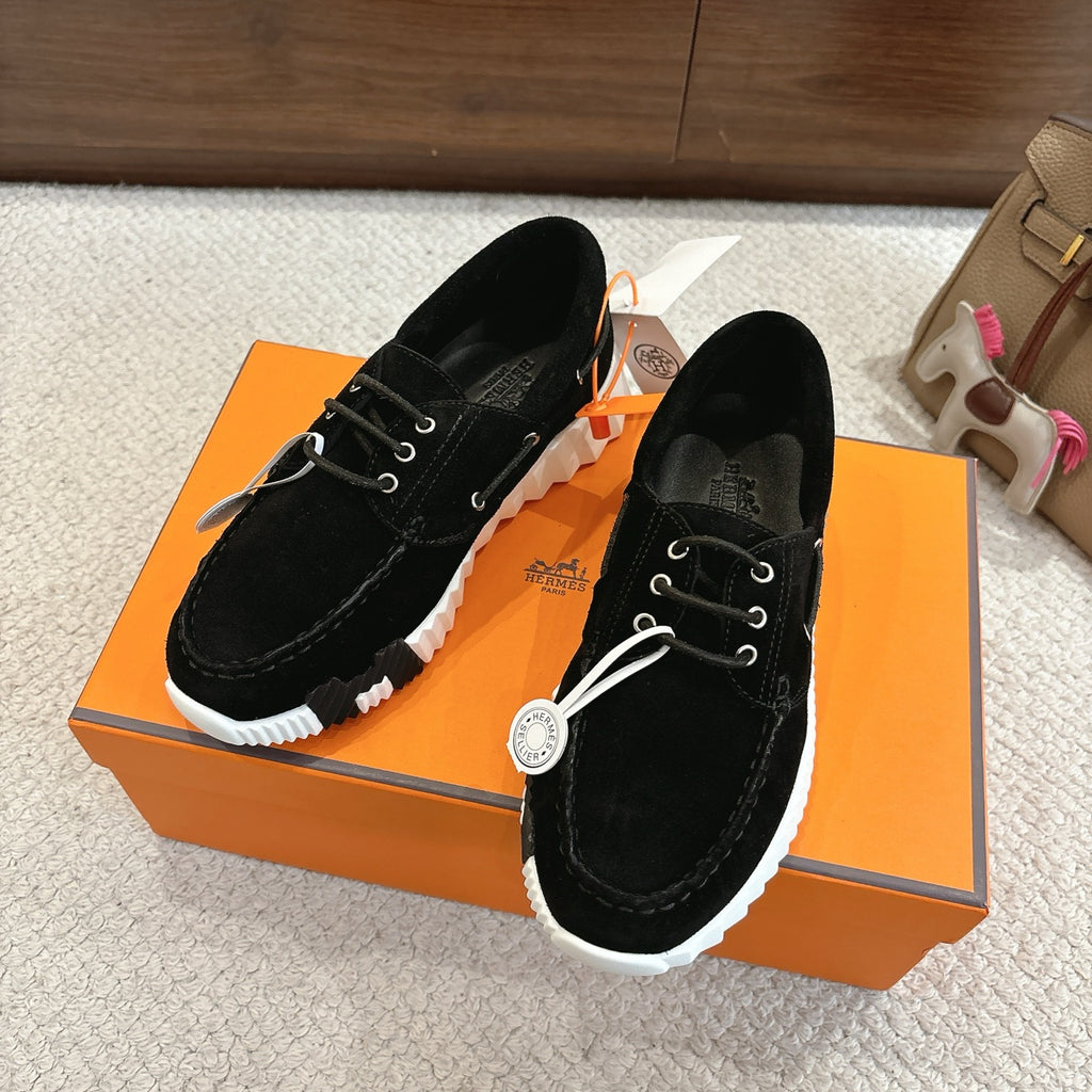 Black lace-up unisex sneakers on orange box, white chunky sole and eyelets