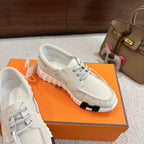 Light beige lace-up sneakers on an orange box, side view of ribbed sole