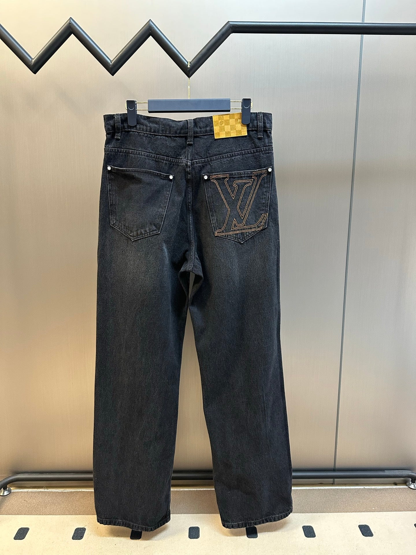 Dark blue denim pants with large LV monogram patch on the front leg