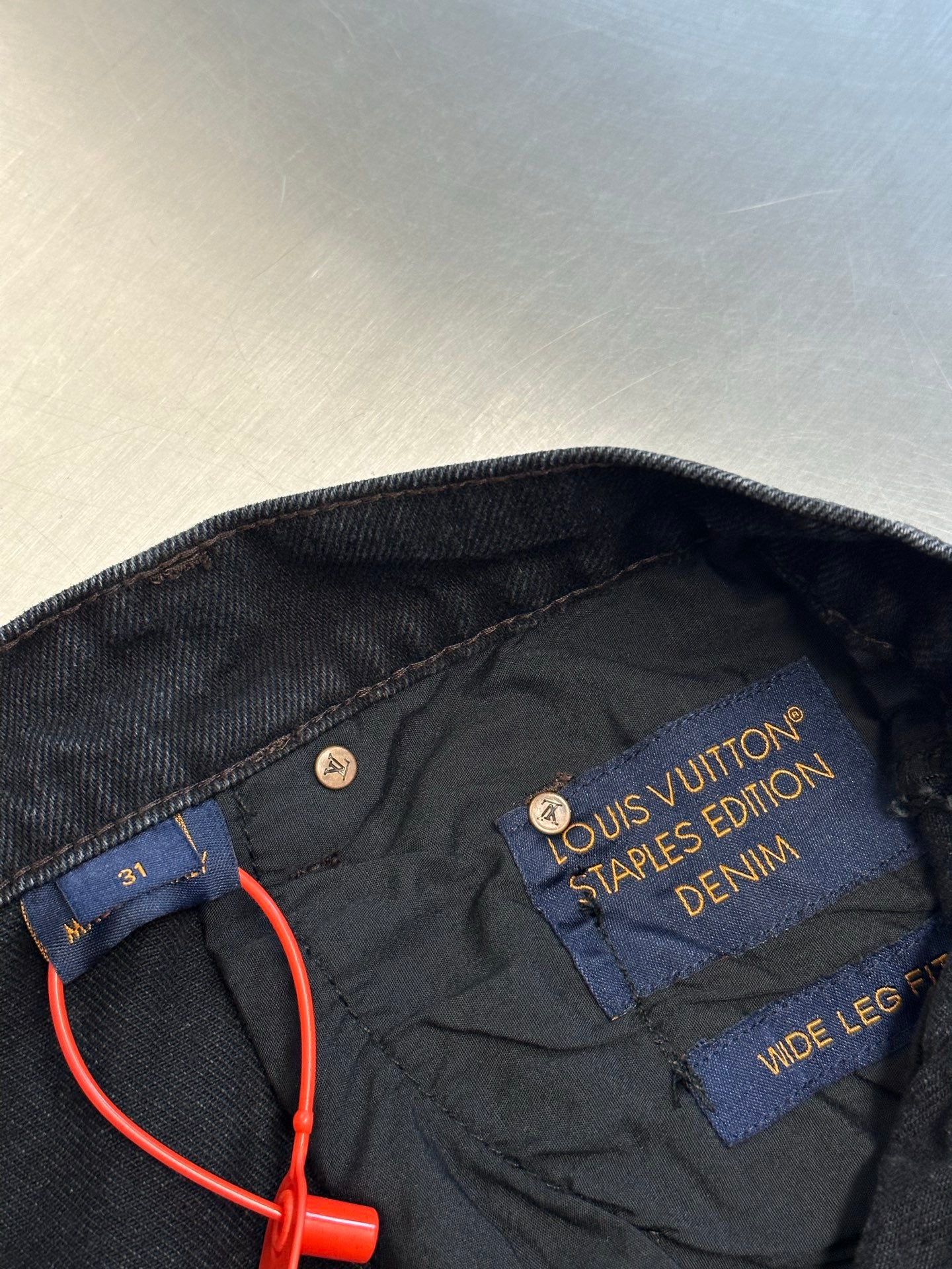 Dark blue denim pants with interior Louis Vuitton Stamped Denim label and orange cord