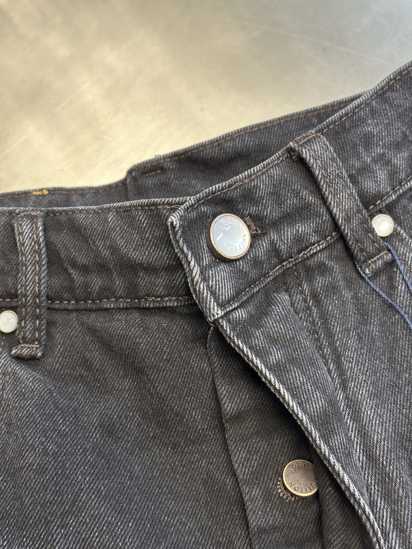 Dark blue denim pants waistband with snap buttons and metal hardware