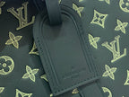 Louis Vuitton green leather luggage tag with embossed logo on patterned bag