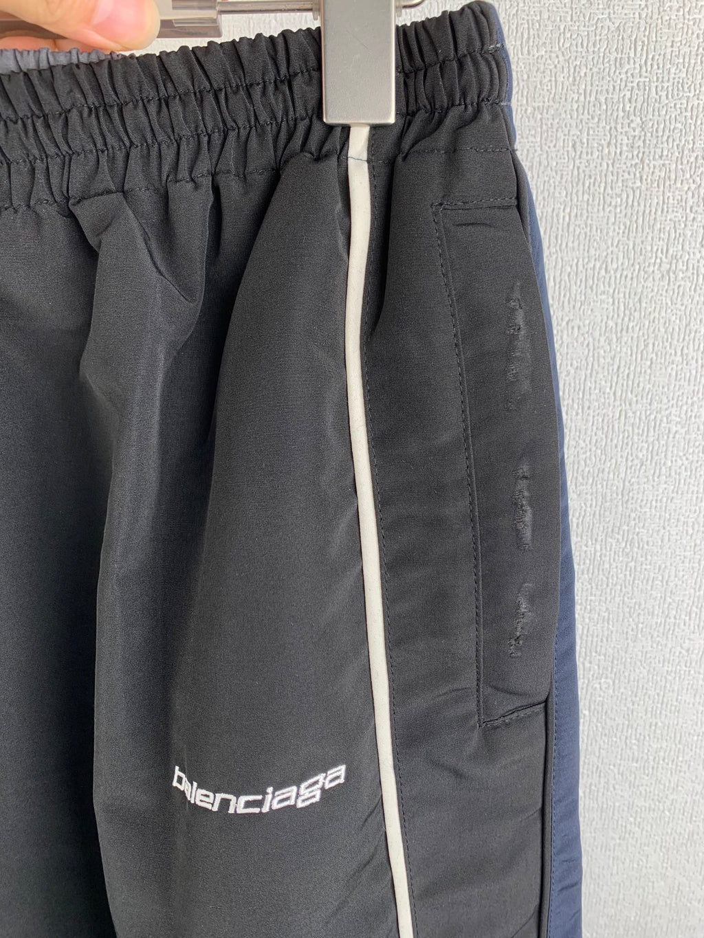 Balenciaga track pants close-up: elastic waistband and front logo patch