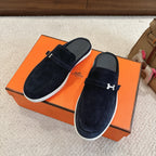 Hermes unisex suede loafers with dark blue upper, H-buckle strap, and white trim sole.