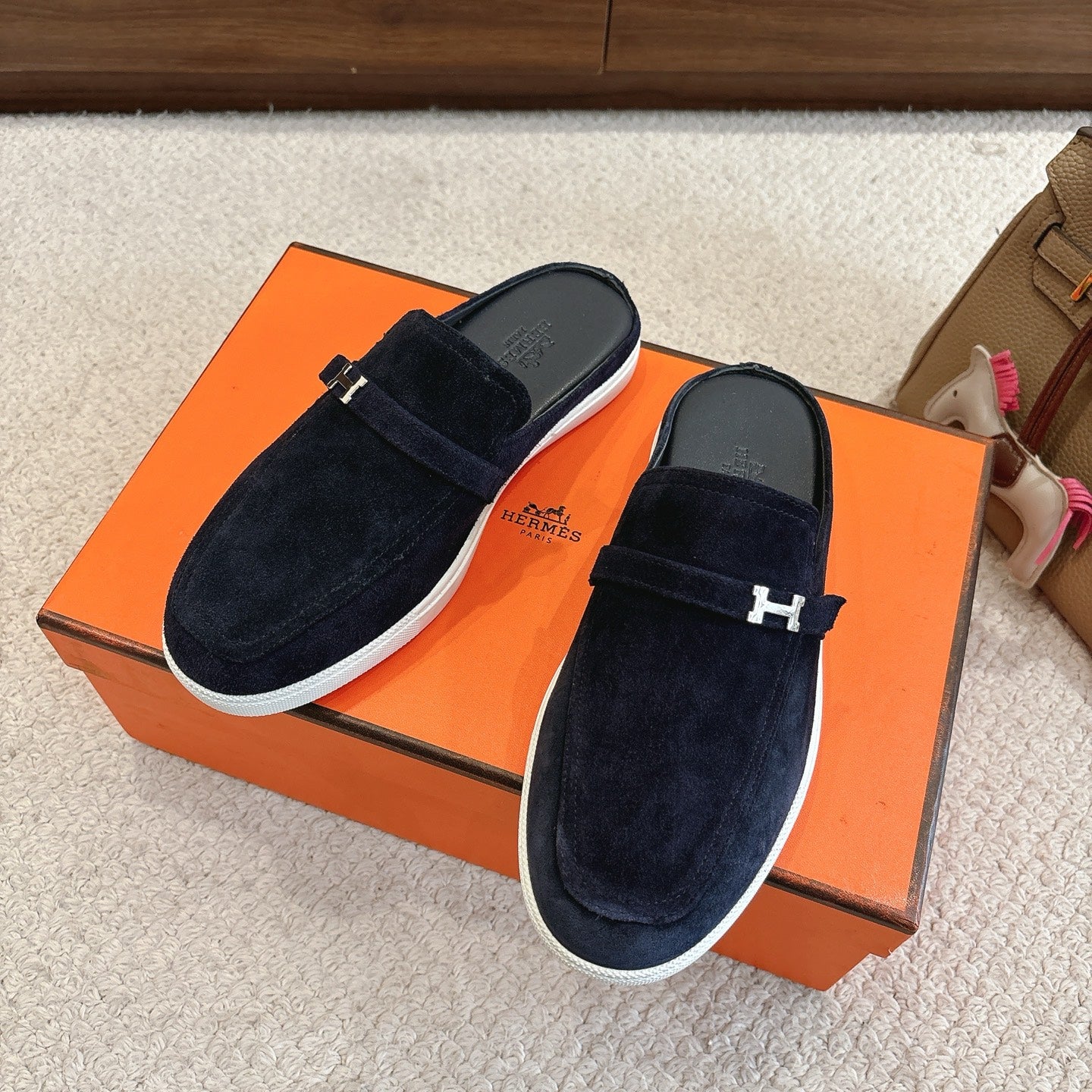 Hermes unisex suede loafers with dark blue upper, H-buckle strap, and white trim sole.