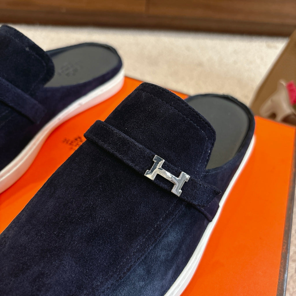 Hermes unisex loafer close-up: dark blue suede with silver-tone H buckle on strap.