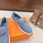 Blue suede loafer with stitched apron and metal buckle strap, close side view