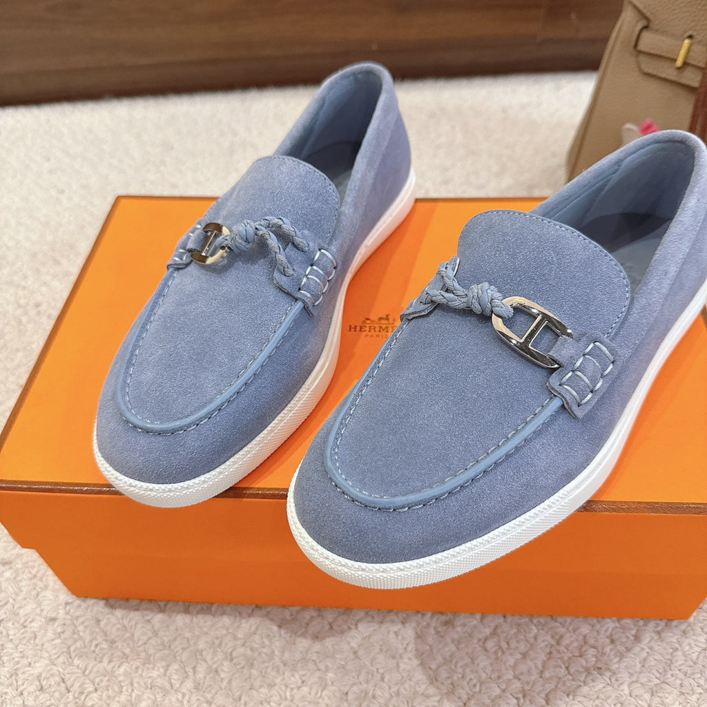 Pair of light blue suede loafers with metal buckle strap and white soles