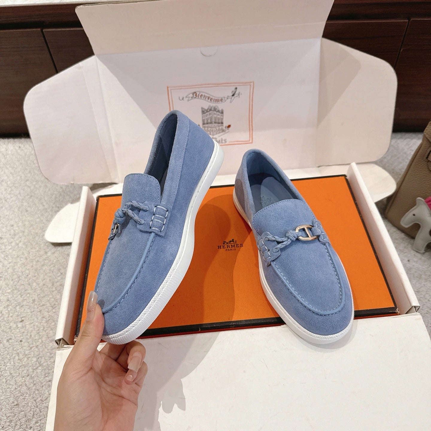 Light blue suede loafers with metal buckle strap, viewed from side