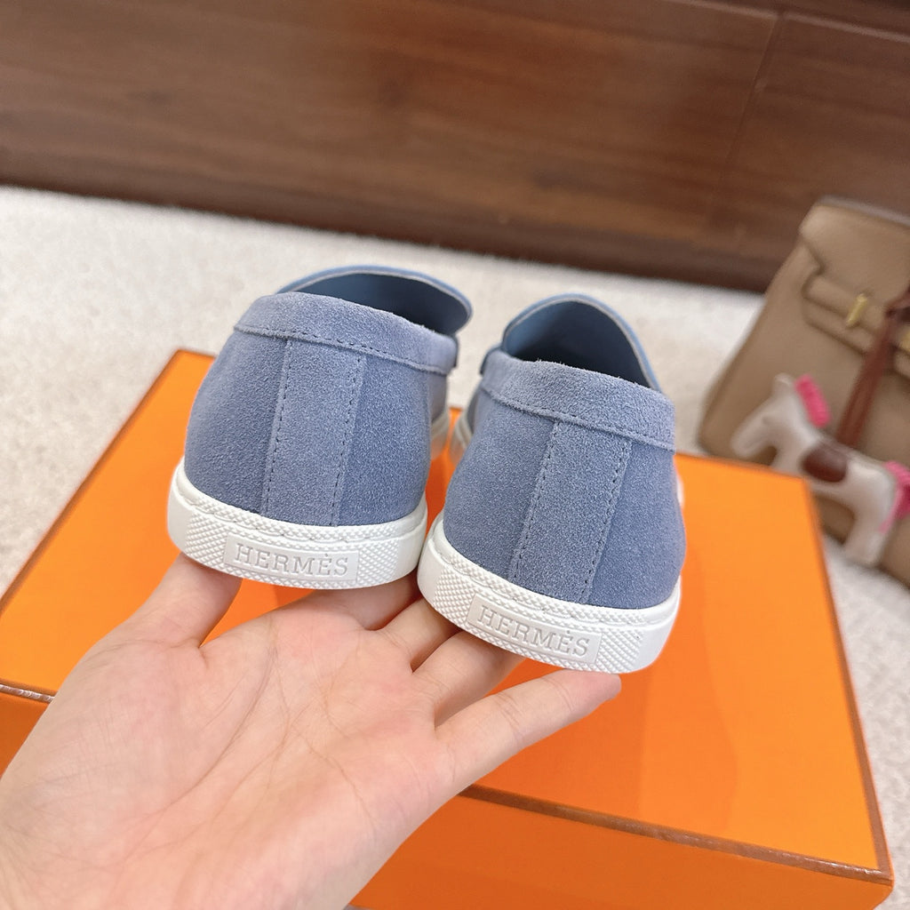 Back view of blue suede loafers with white rubber heel and logo print