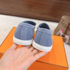 Back view of blue suede loafers with white rubber heel and logo print