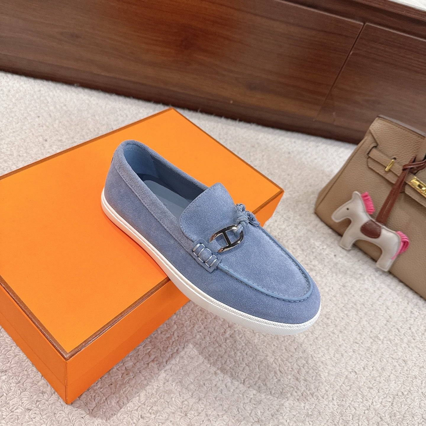 Light blue suede loafers with gold-toned buckle and braided laces, angled