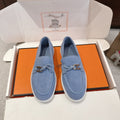 Blue suede loafers with gold buckle detail and white rubber sole pair