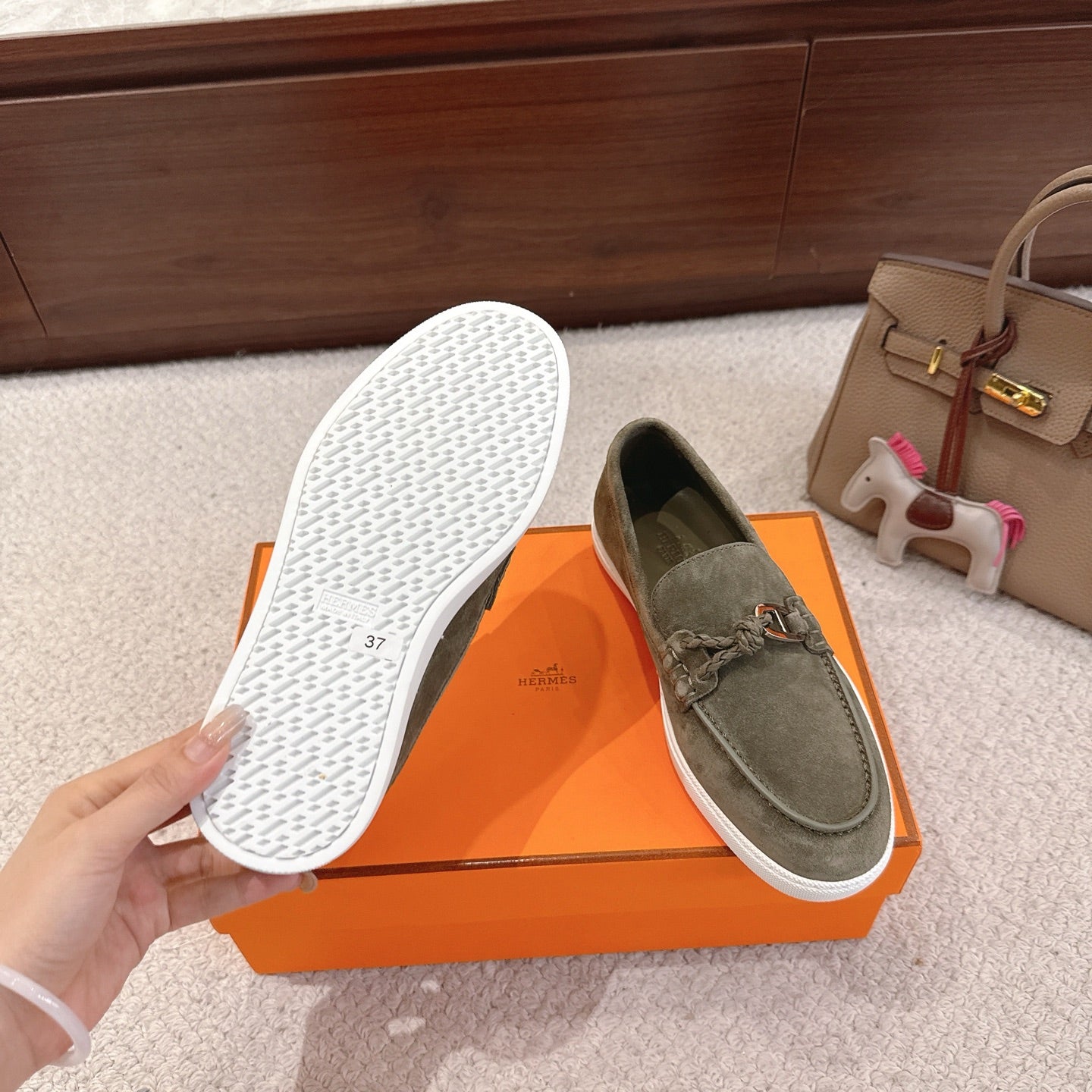 Hermes suede loafers with one shoe sole shown; dark olive uppers on orange box