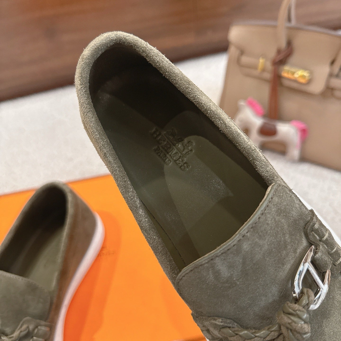 Hermes suede loafer upper in dark olive green, close-up of metal bit and stitched laces